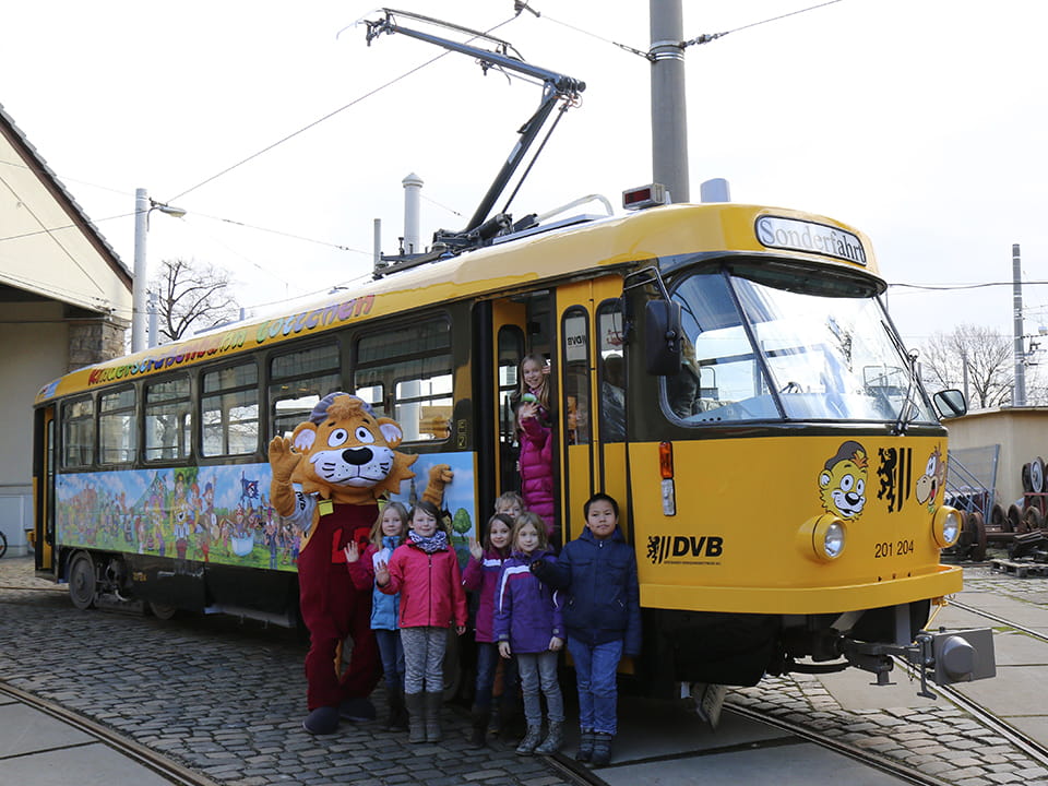 DVB-Maskottchen mit Kindergruppe vor Kinderstraßenbahn