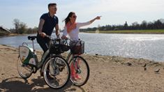 Mann und Frau auf Leihfahrrädern an der Elbe