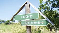 Wegweiser nach Poedemus und zur Zschonermühle vor sommerlicher Wiese