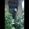 Foto eines Grabstein mit einer Frauenstatue, welche rote Blumen in der Hand hält.