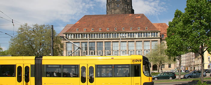 Das Foto zeigt eine gelbe Straßenbahn vor dem Dresdner Rathaus.