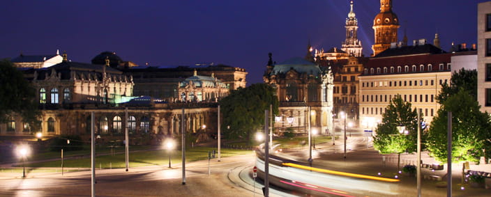 Zdjęcie pokazuje Postplatz z kompleksem Zwinger i zamkiem nocą.