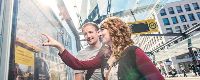 The photo shows two passengers reading the network map at a stop