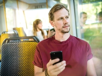 Nachdenklicher Mann in der Bahn mit Handy in der Hand