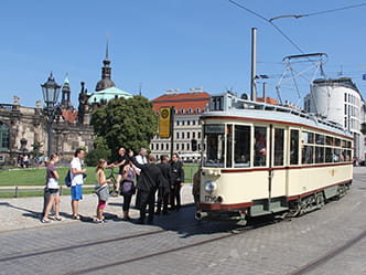 Das Foto zeigt eine historische Straßenbahn gegenüber des Dresdner Zwingers.