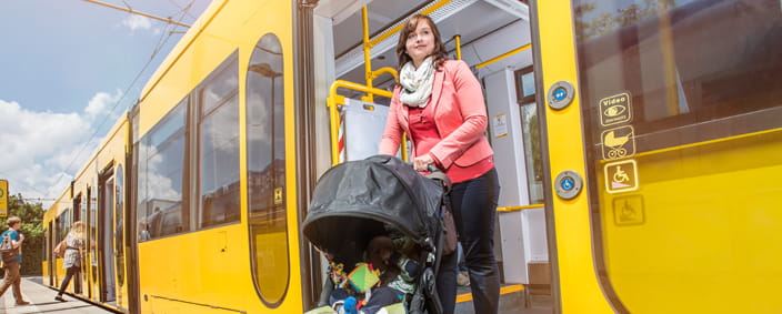 Zdjęcie kobiety z wózkiem dziecięcym wysiadajacej z tramwaju. 