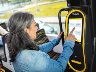 eine Frau kauft sich ein Ticket am mobilen Ticketautomaten