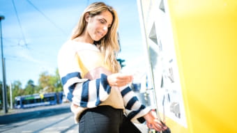 eine Frau kauft sich ein Ticket am stationären Ticketautomaten