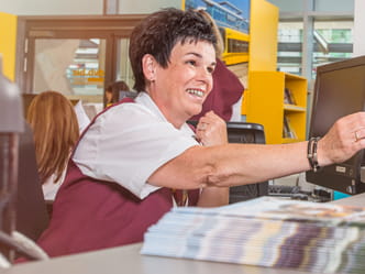 The photo shows a customer service employee at a ticket counter