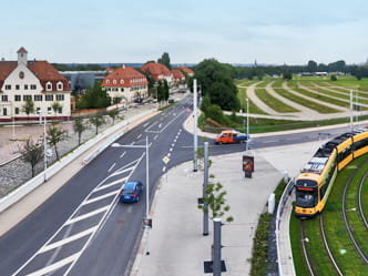 Das Foto zeigt eine Straßenbahn und den Kreuzungsbereich an der Messe Dresden aus einer Vogelperspektive.