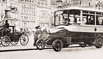 Historischer Bus und ein Auto vor städtischer Bebauung