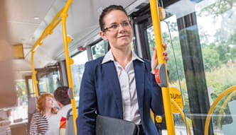 Frau in Hemd und Jacket und mit Geschäftsunterlagen in der Hand fährt Bus