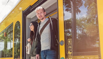 Zwei junge Menschen verlassen steigen aus einer Straßenbahn aus