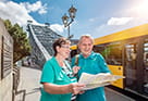 Photo of a couple standing in front of the Blue Wonder bridge studying a map