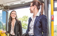 Zwei Frauen in Geschäftskleidung stehen im Eingangsbereich eines Busses